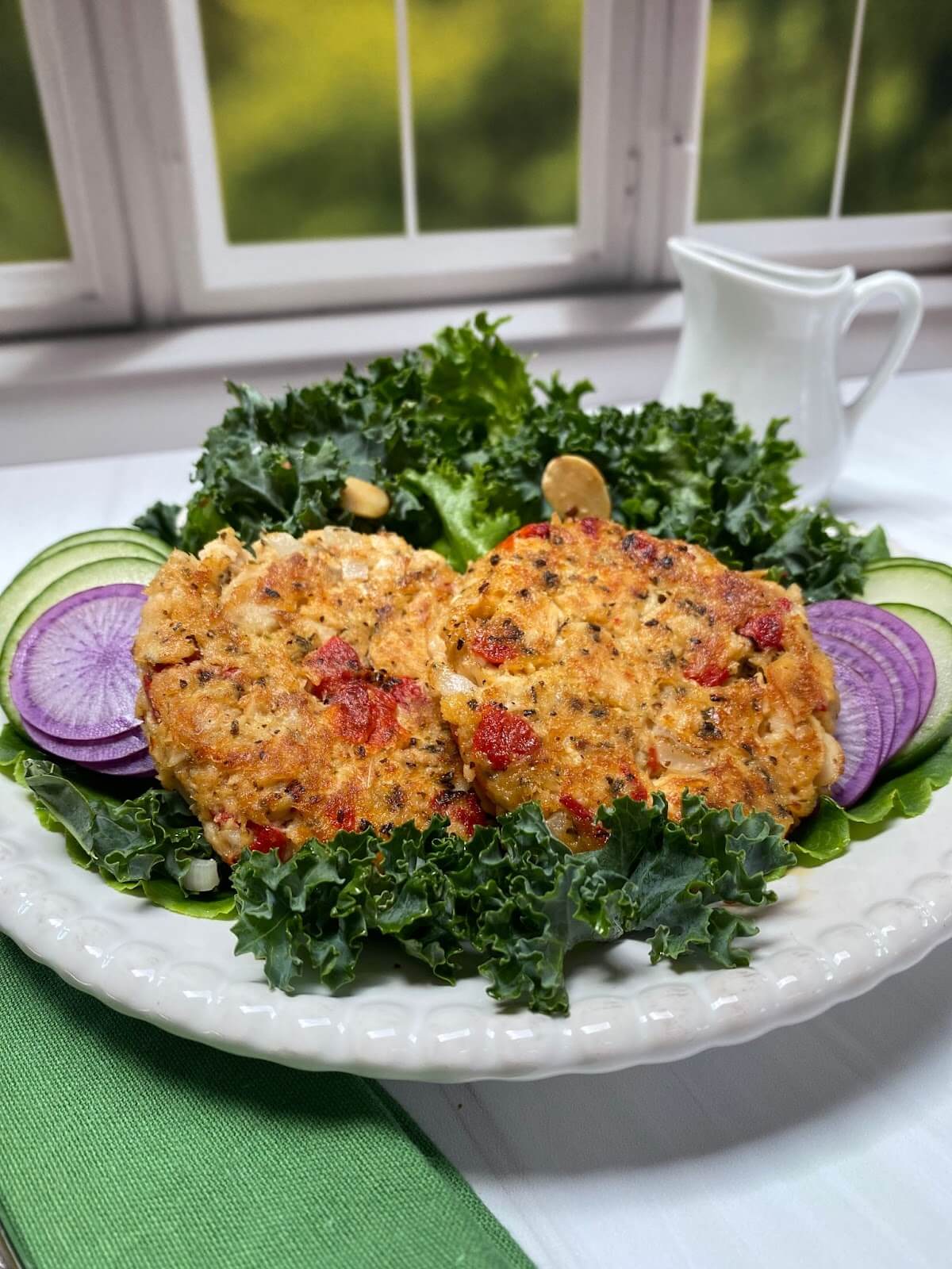 salmon cakes and sliced vegetables on a dinner table