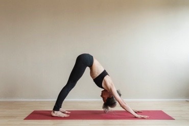 woman in black sportwear doing the downward-facing dog pose