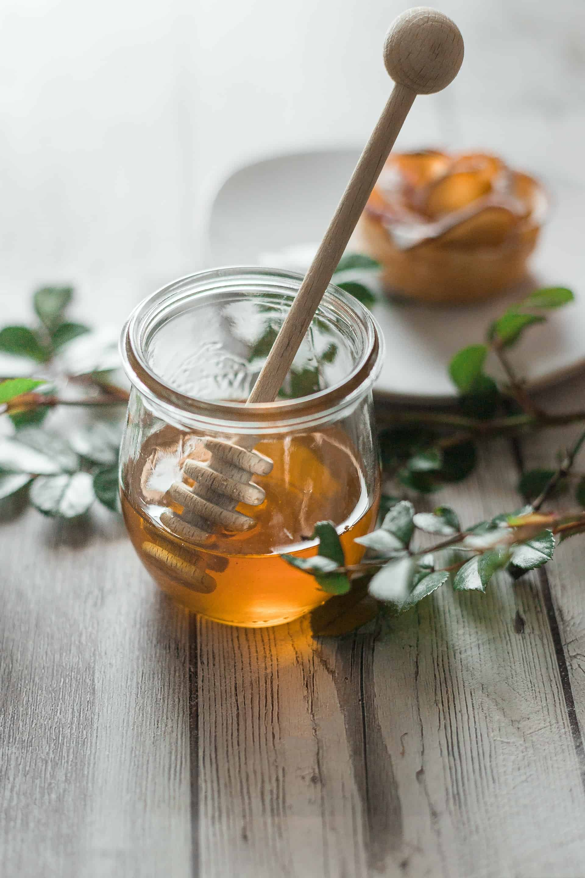 glass-of-honey-on-wooden-table-with-branches-on-it