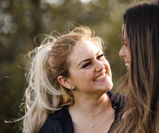 Woman smiling and talking to a friend while on a walk in a park