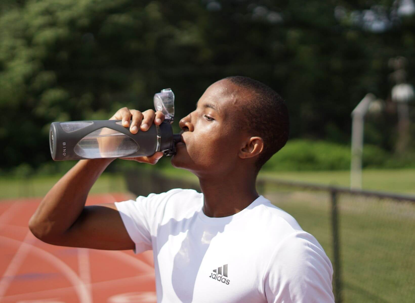 A black man drinking water from a reusable water bottle