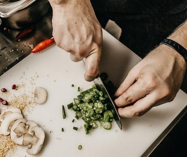 Man chopping vegetables on a white cutting board