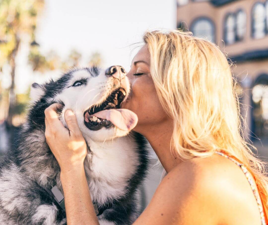 woman kissing a dog outdoors