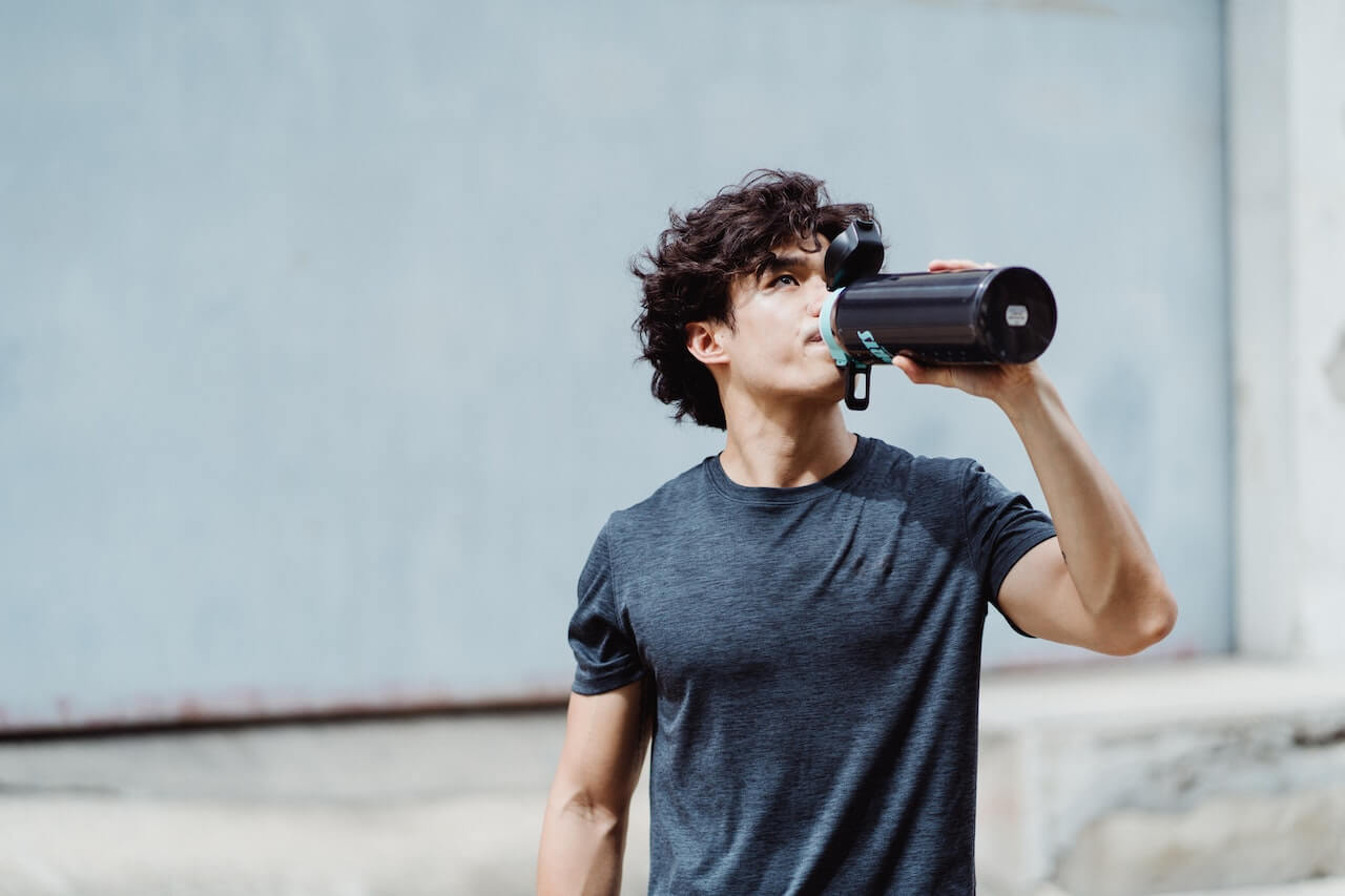 Young-man-drinking-electrolyte-water-after-work-out