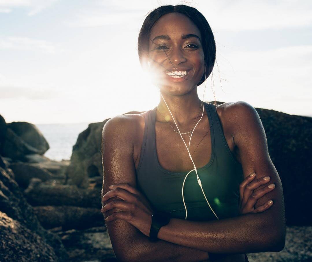 woman in workout clothes standing outside and smiling