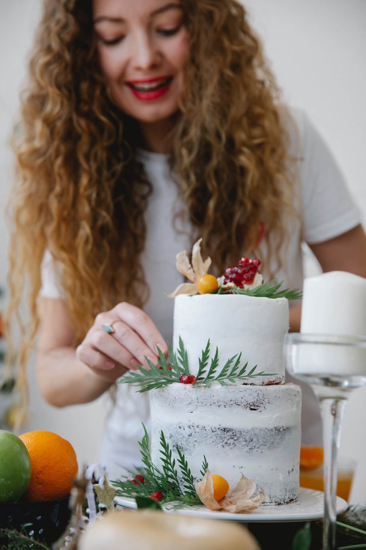 Woman-decorating-christmas-cake-with-berries-and-herbs