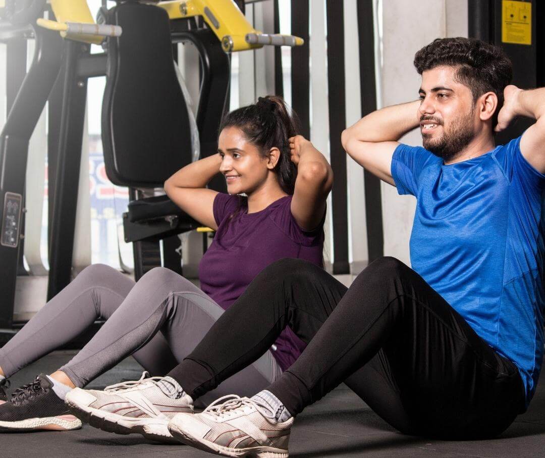 a man and a woman doing sit-ups in a gym setting