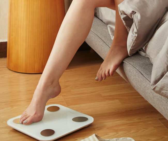 Woman stepping on a smart scale as she gets out of bed