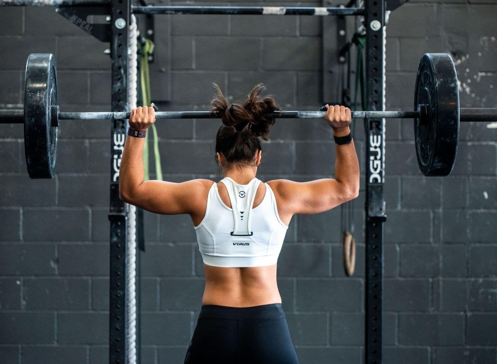 Woman powerlifiting a heavy barbell over her head. This is an example of anaerobic exercise.