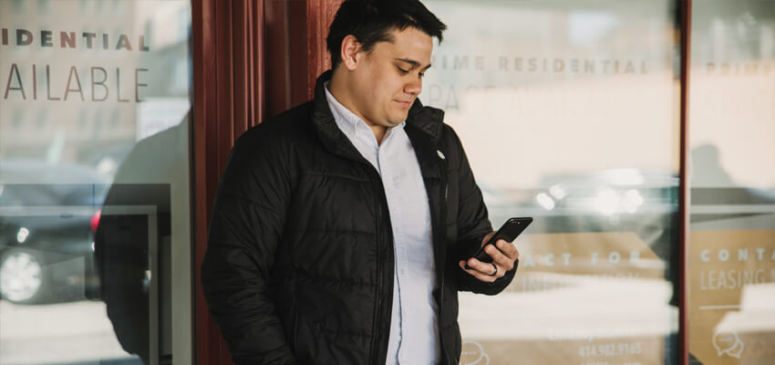 Man standing in on an urban street, pre-tracking meals on his iPhone