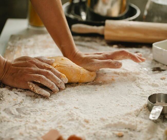 Person kneading bread on a floured countertop