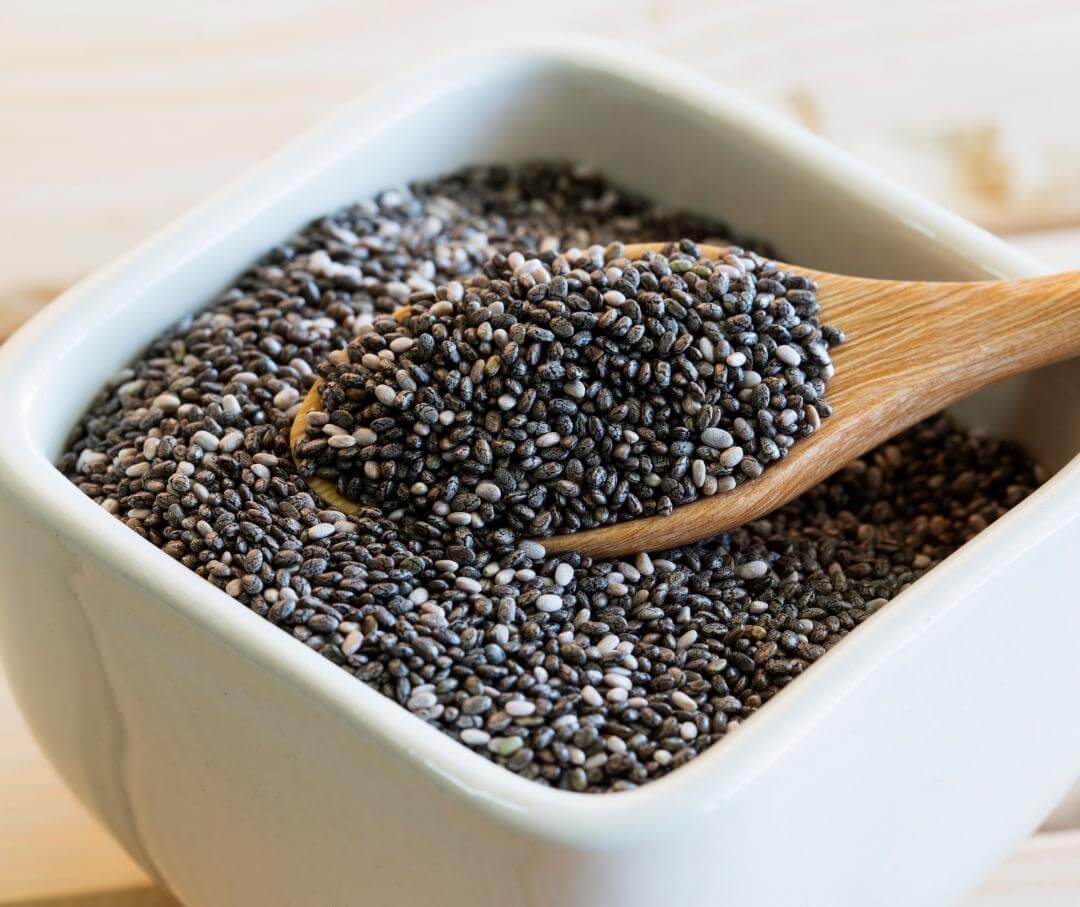 chia seeds in a white dish with a wood spoon