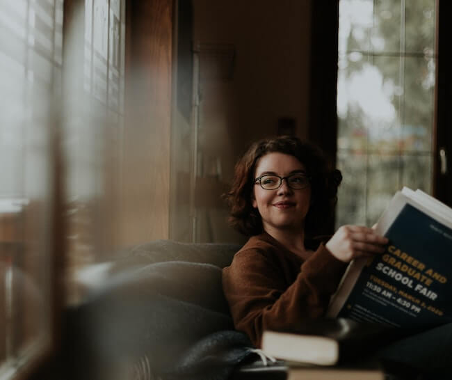 Woman leisurely reading at home on a sofa near a window