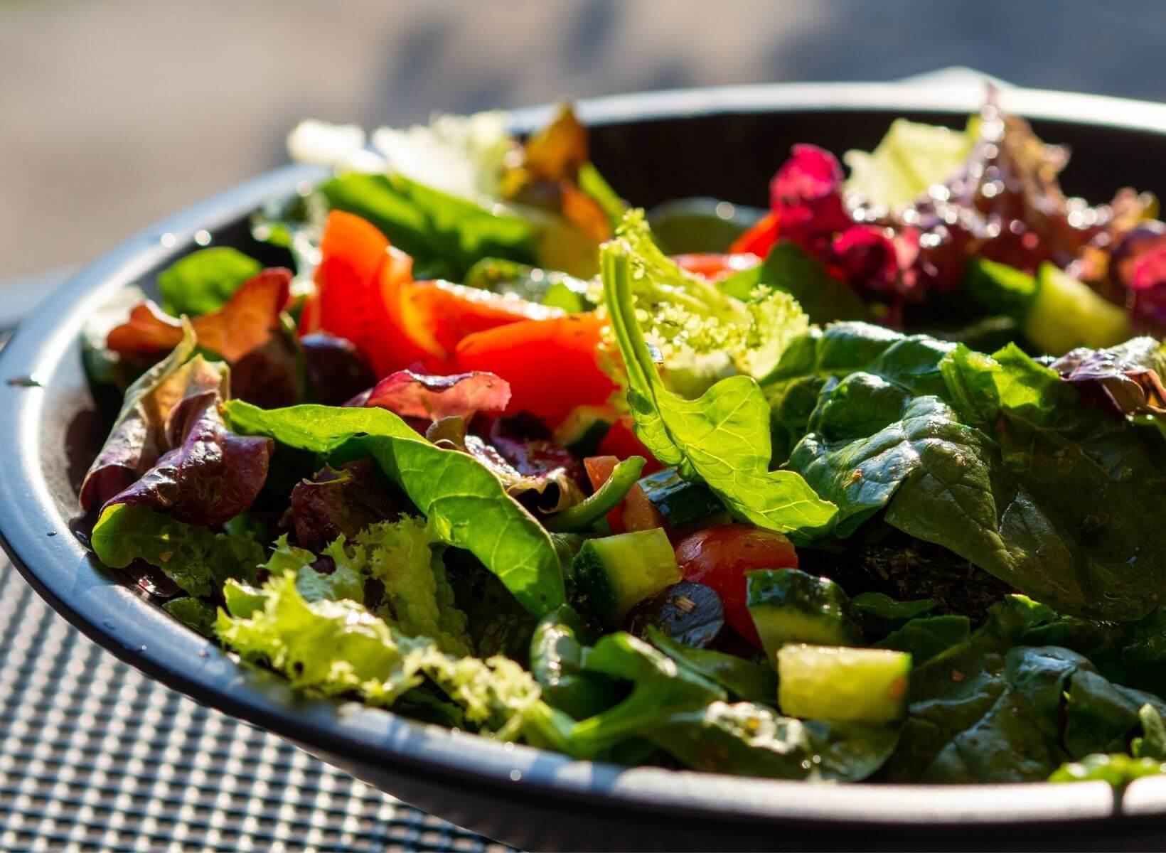 A closeup shot of a black plate piled with Italian chicken mason jar salad