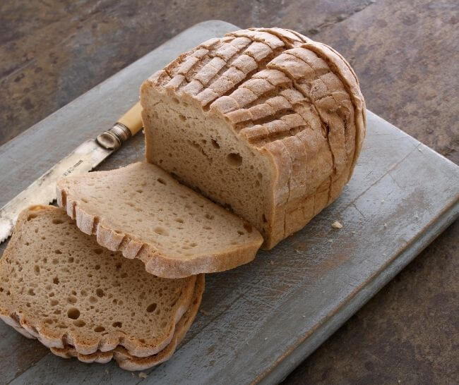 A loaf of gluten-free bread, sliced on a cutting board