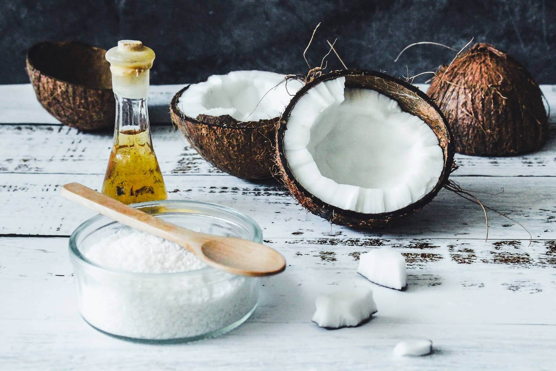 white-table-with-coconuts-a-glass-jar-and-an-oil-bottle-on-it