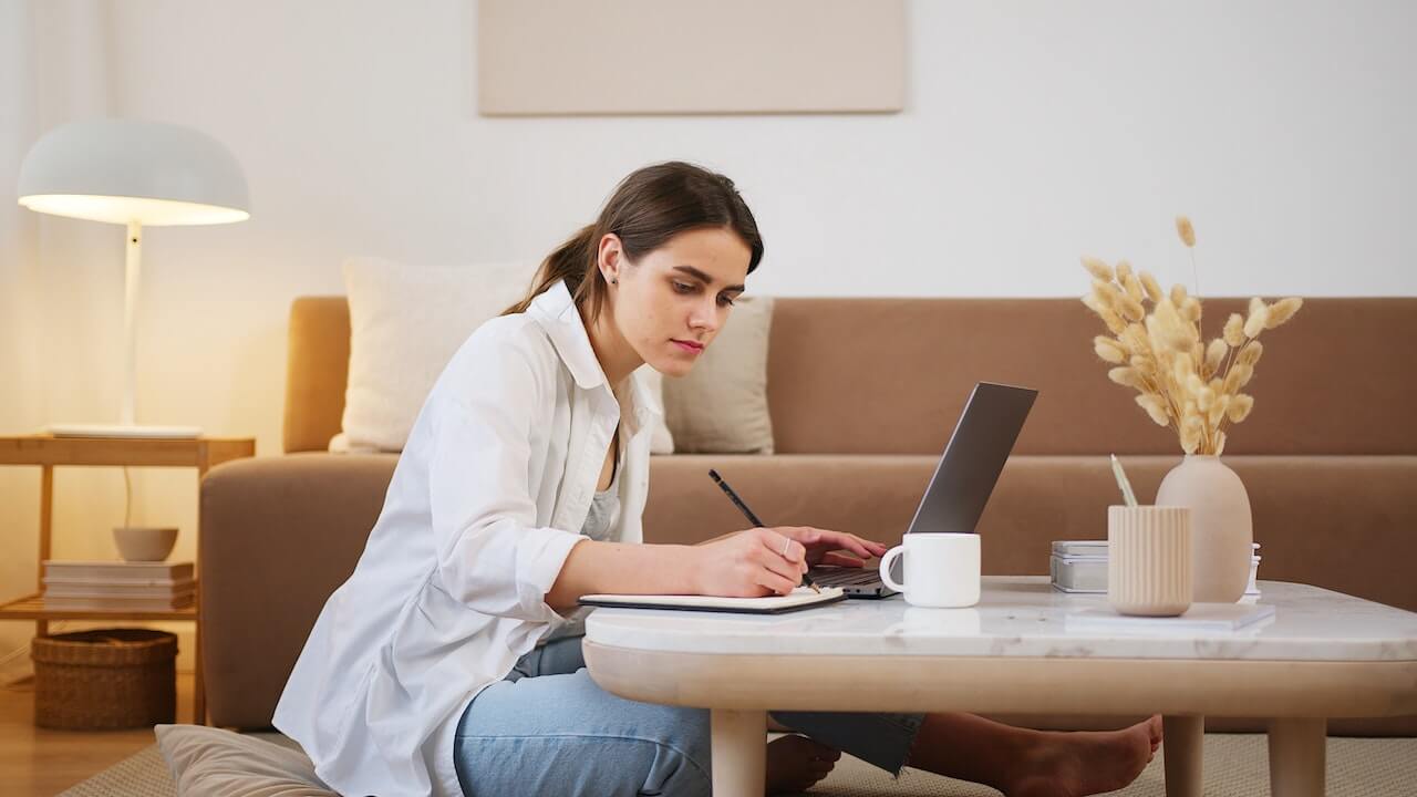 Young woman in front of laptop taking notes 