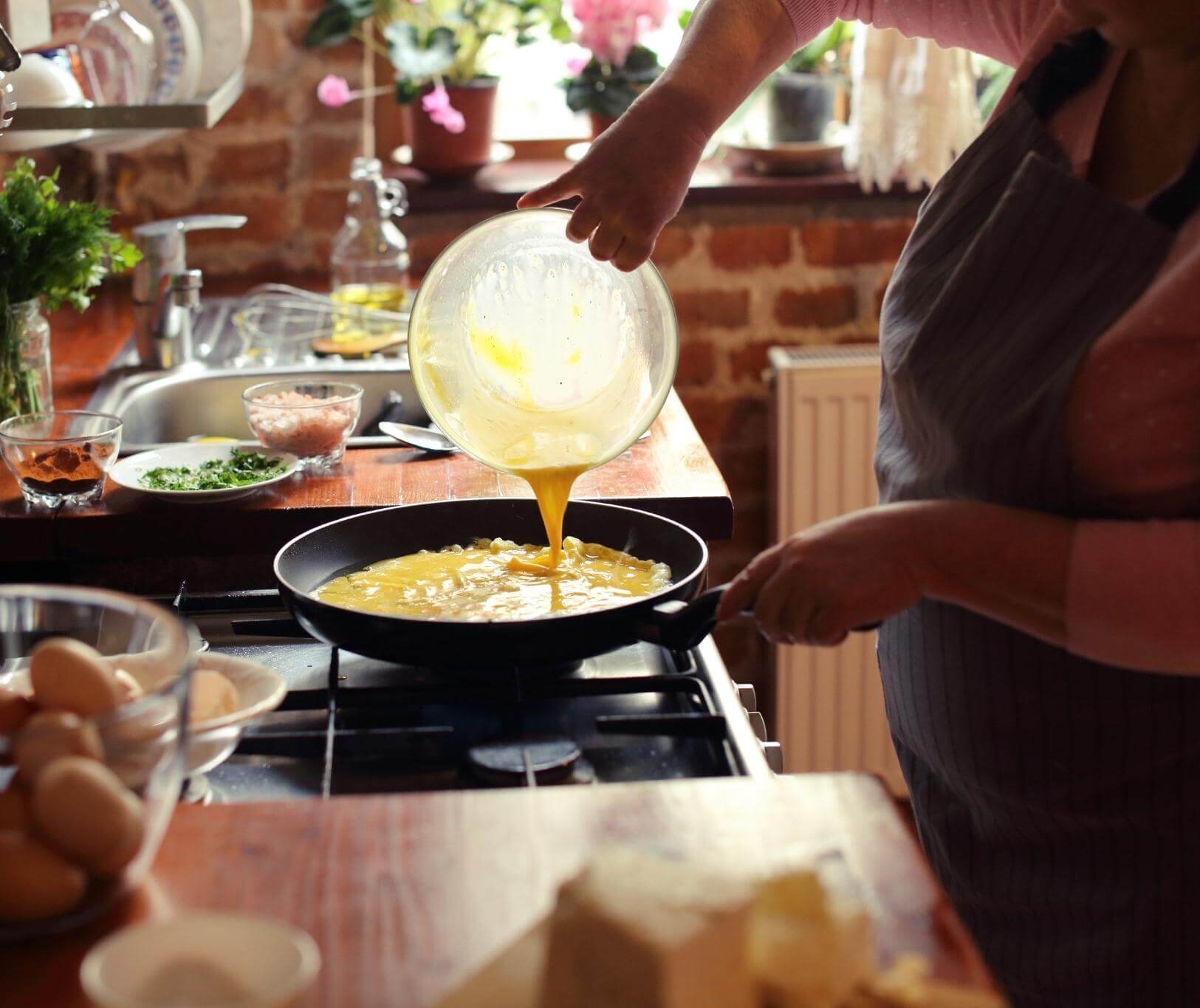 pouring beaten eggs into a pan on the stovetop