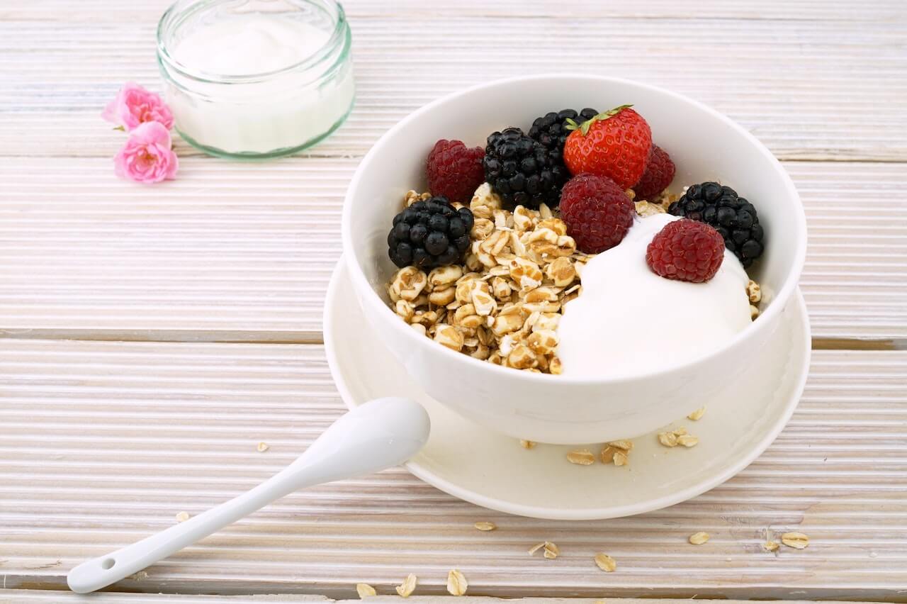 A bowl with yougurt with raspberries and blueberries