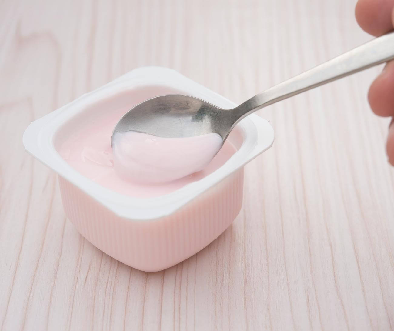 Person scooping flavored yogurt—an ultra-processed food—out of container