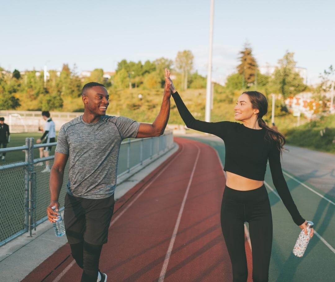 a man and a woman giving each other a high-five on a running track