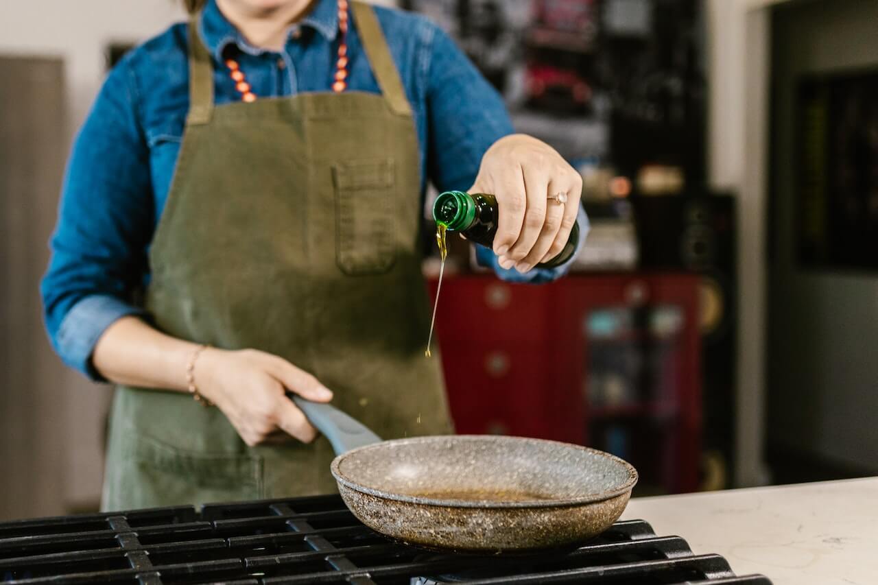 Chef pouring olive oil into pan