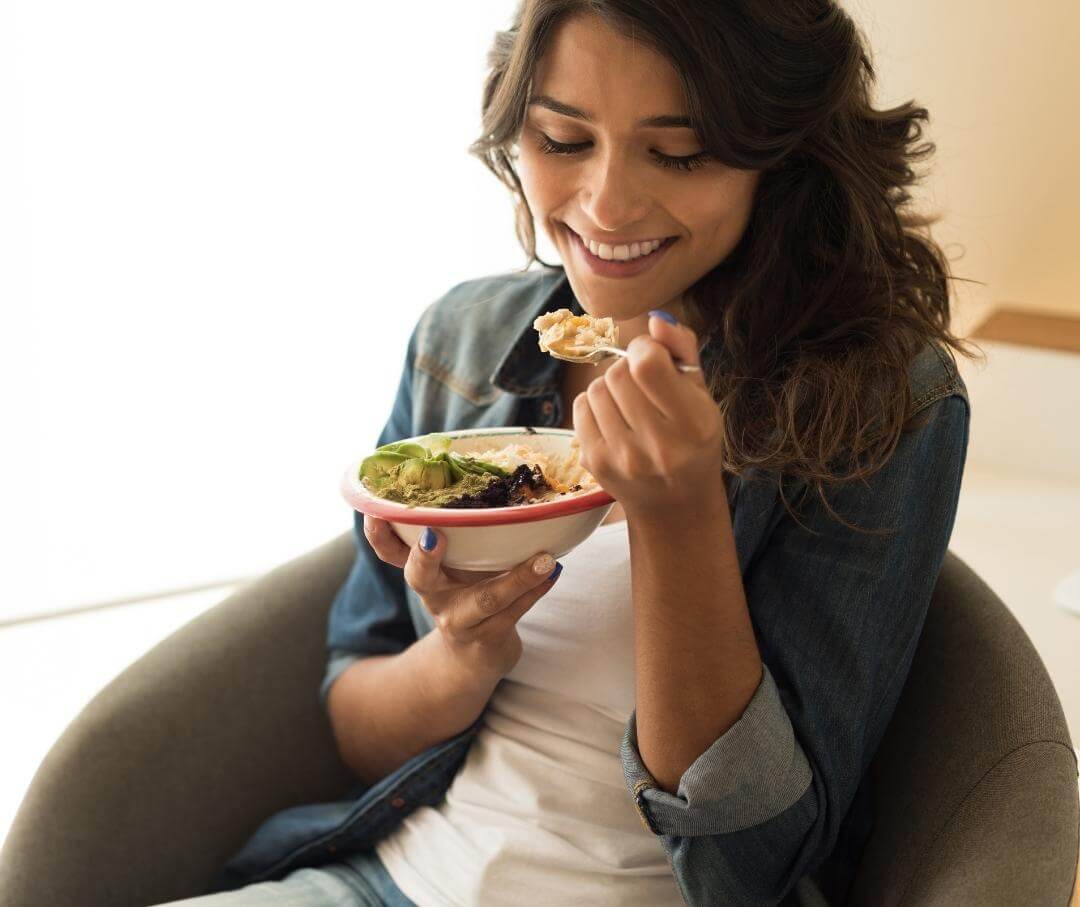 a woman sitting on a chair eating a bowl of food