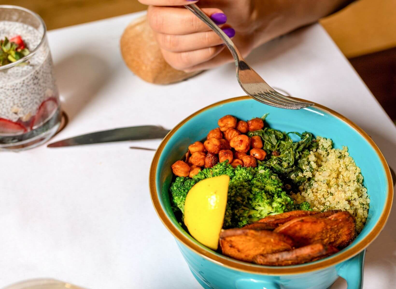 A hand holding a fork over a bowl of chickpeas, vegetables, and quinoa, a meal high in probiotics that's good for gut health and weight loss