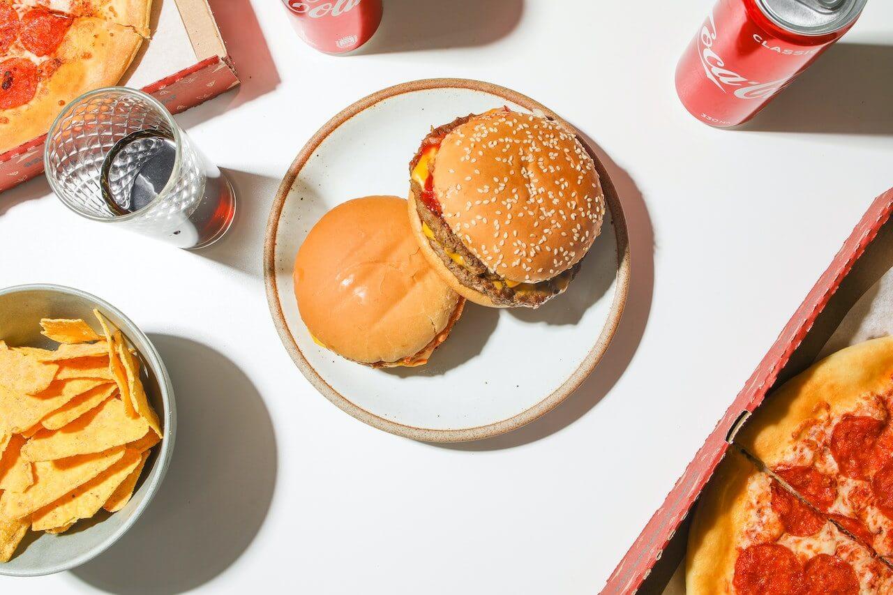 pizza-chips-burger-and-soda-on-white-table