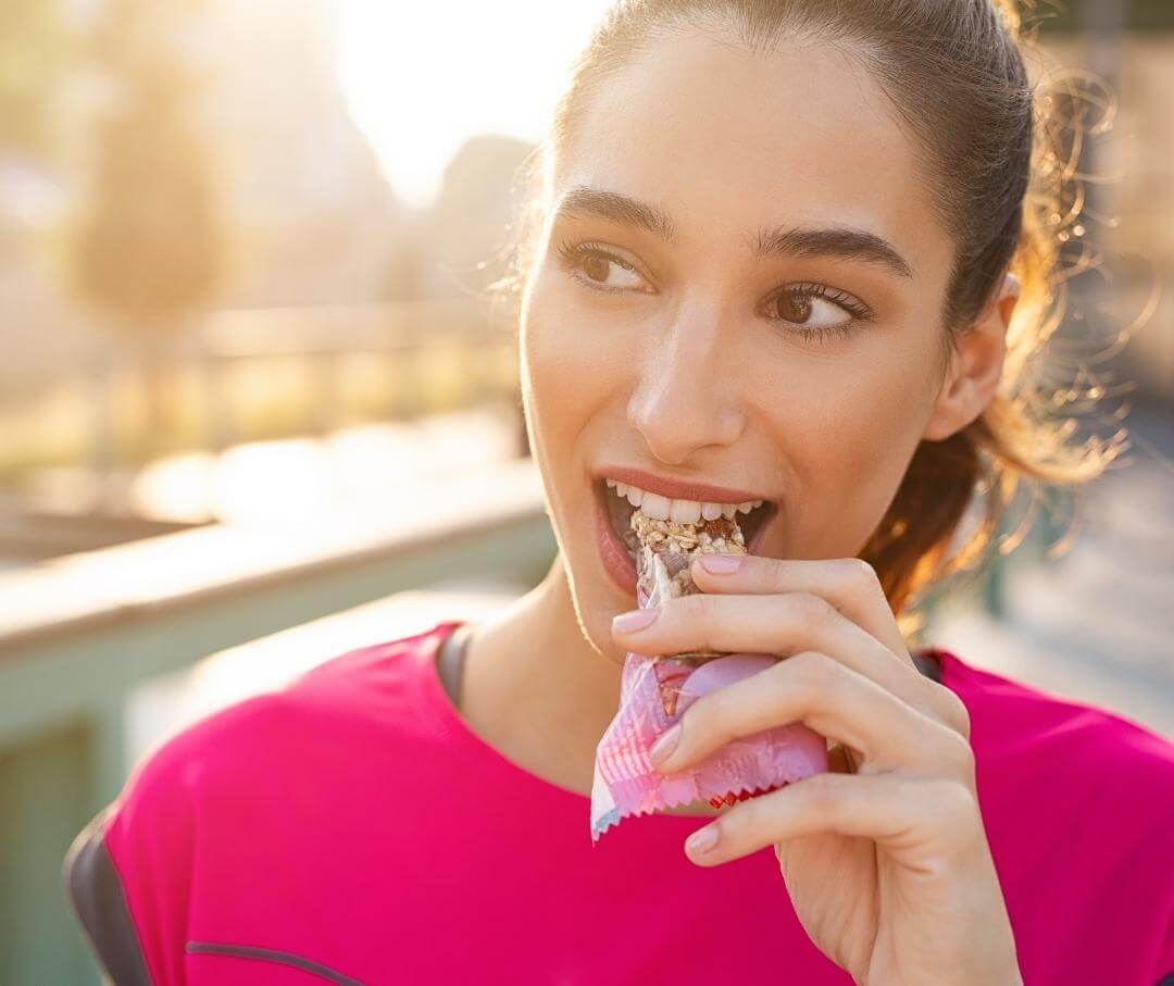 woman biting into a granola bar