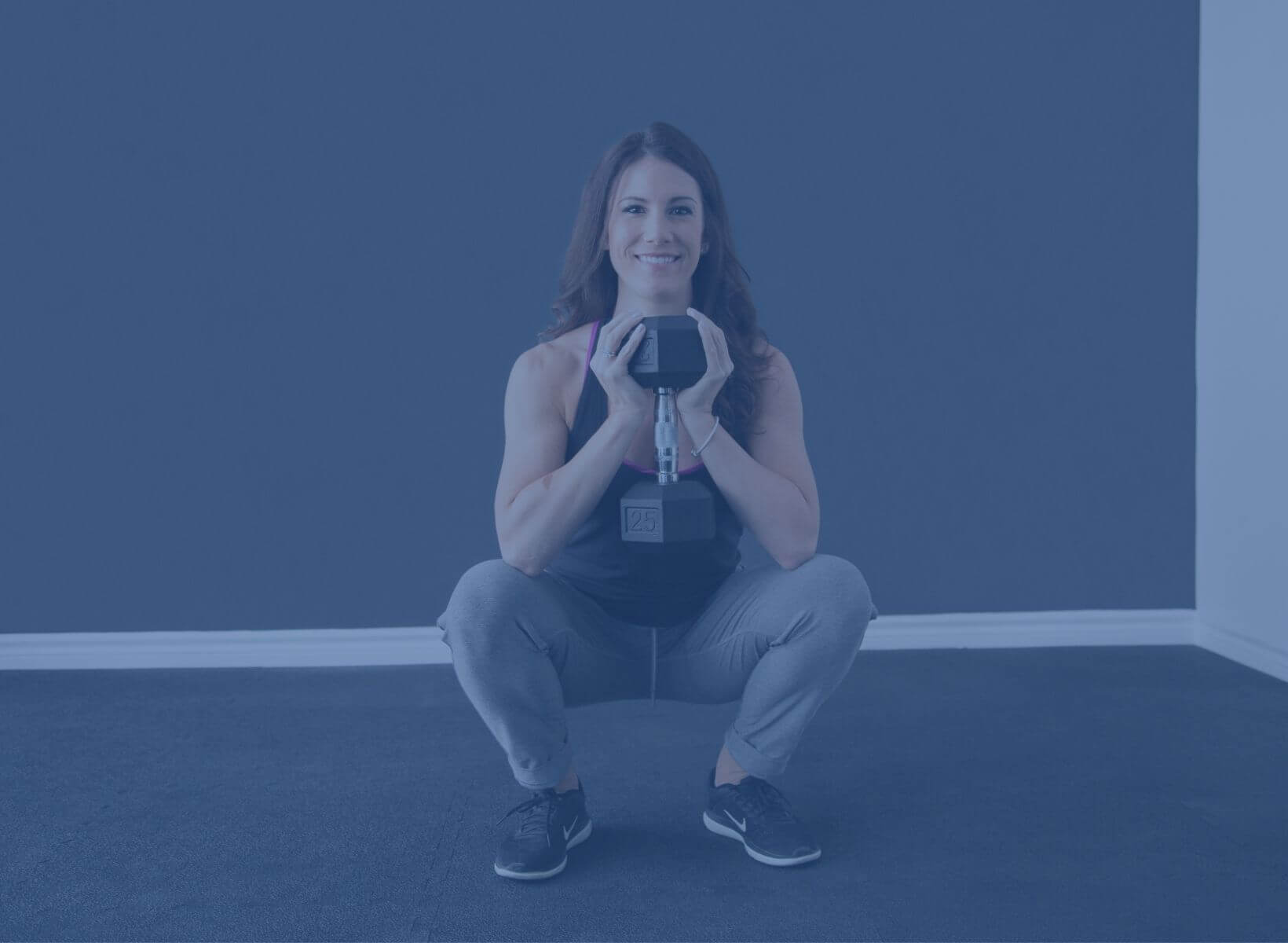 Woman squatting low and holding a dumbbell