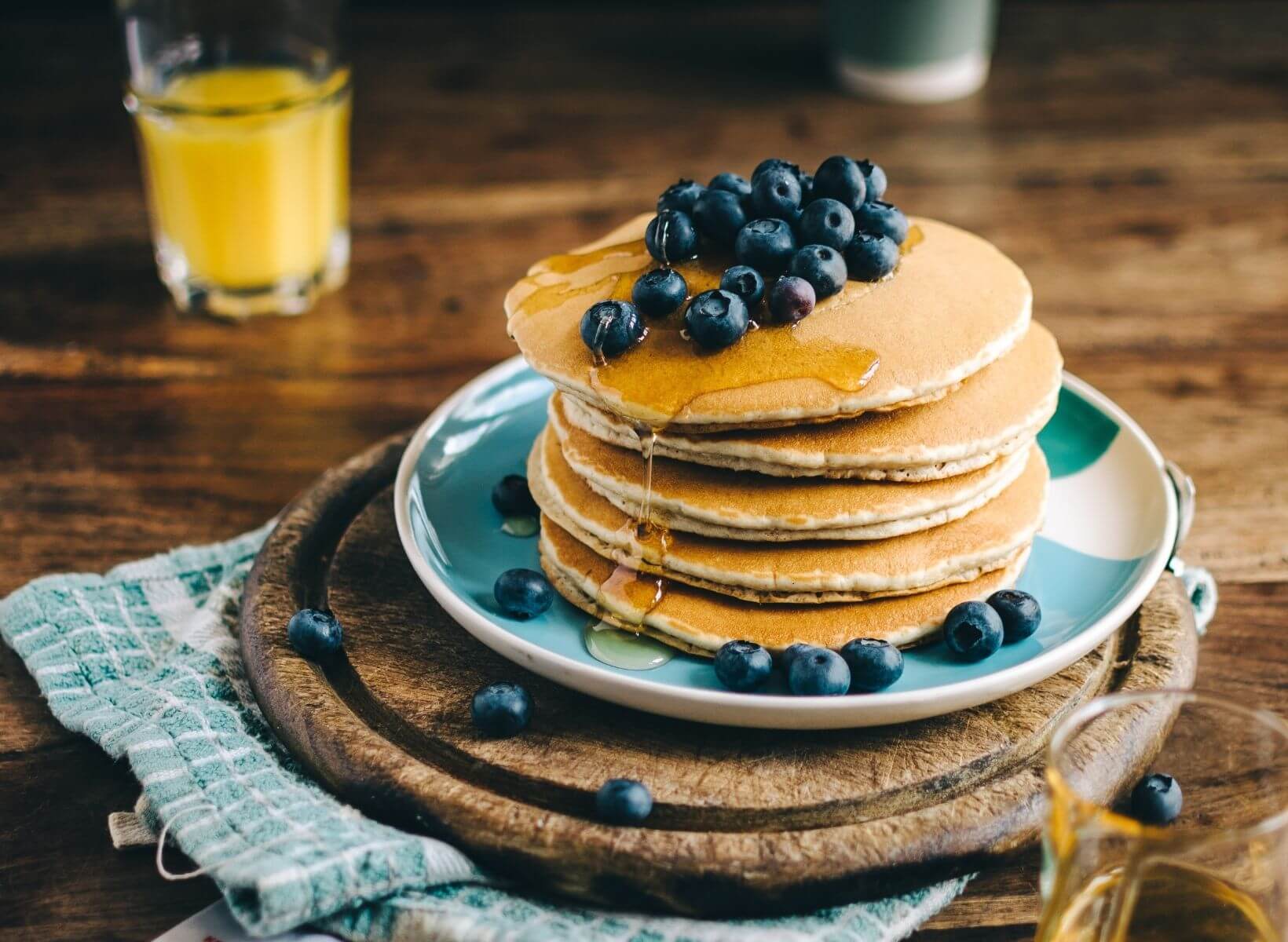 A stack of pancakes with syrup and blueberries, a breakfast that is likely to spike a person's blood glucose