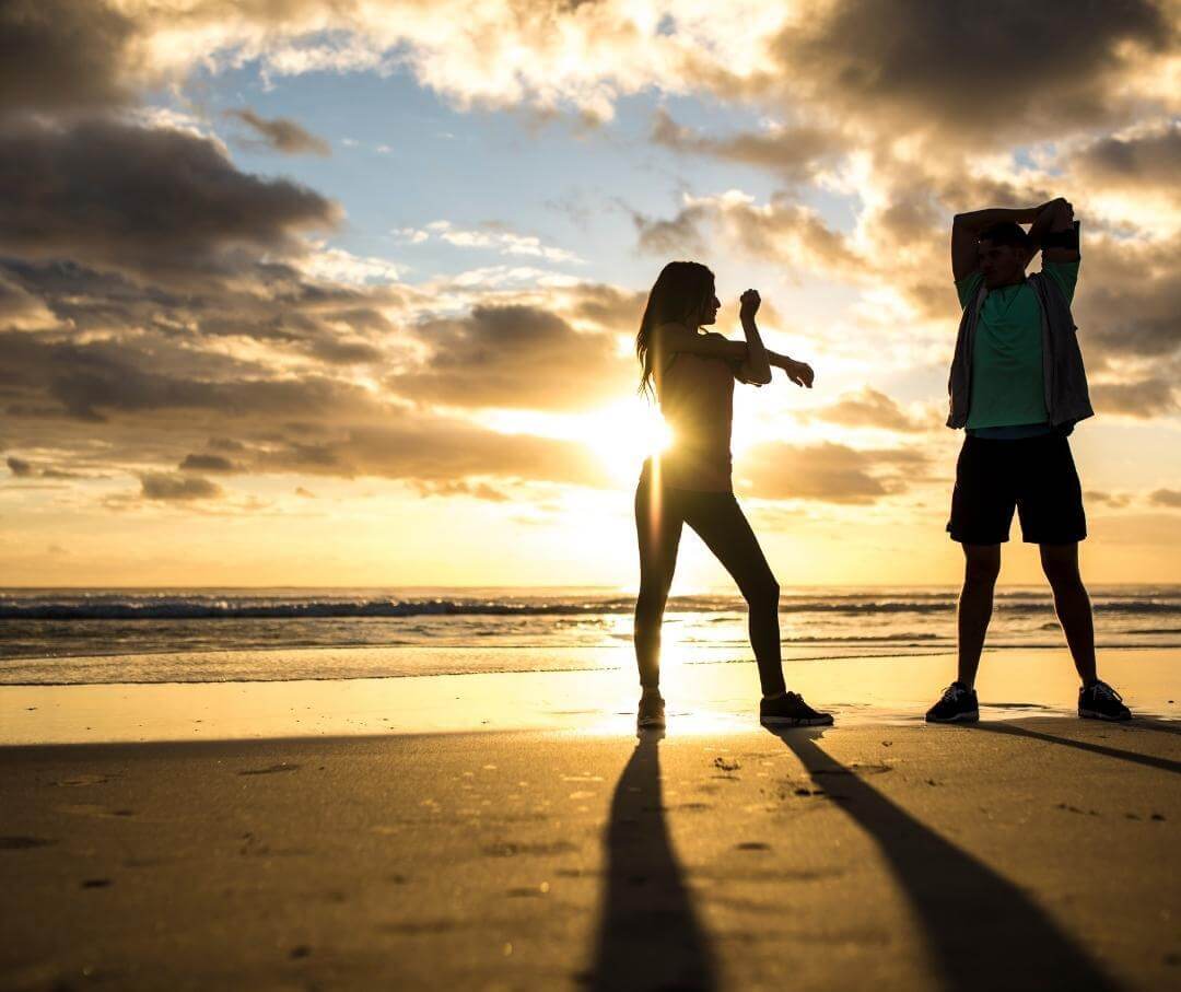 people stretching on the beach in the morning