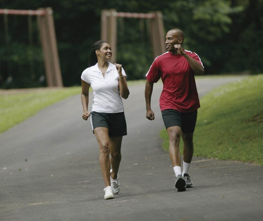 a man and a woman speed walking on a park trail