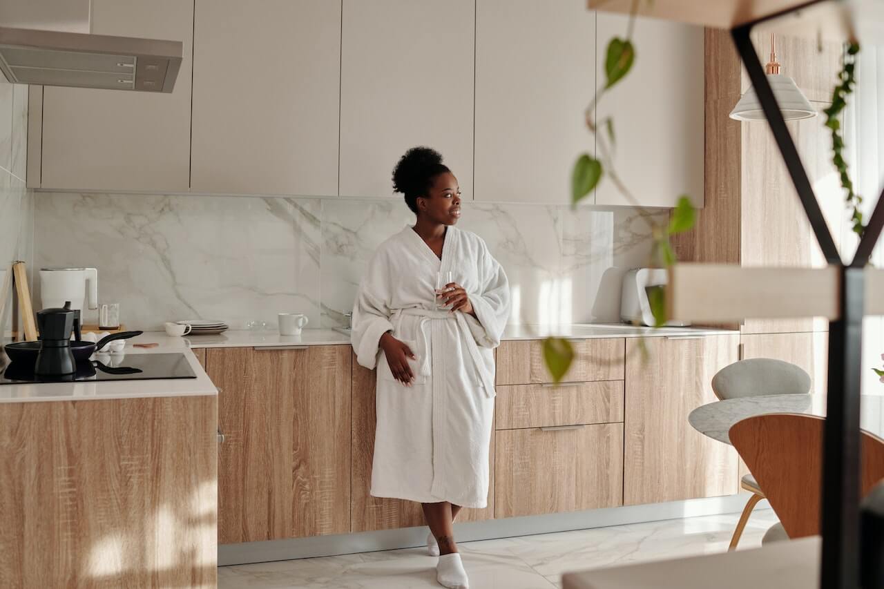 woman-in-robe-drinking-water-in-her-kitchen-in-the-morning