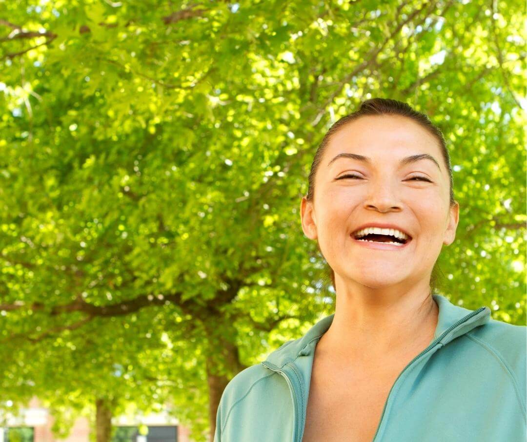 woman standing under a tree and smiling