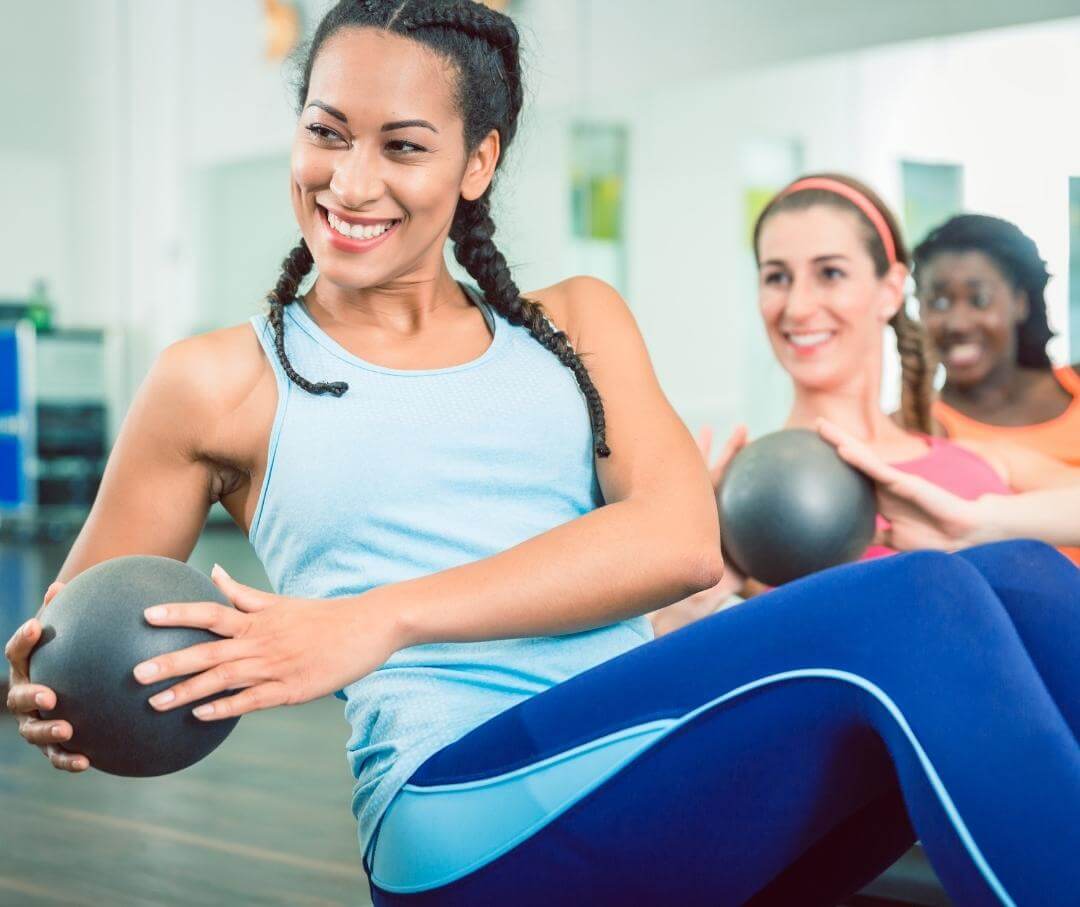 three women using medicine balls in an exercise class