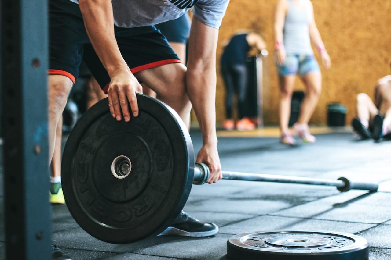 Close-up-of-mans-arms-holding-weight-bar-at-gym