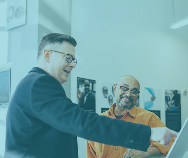 Two men energetically discussing work by a computer