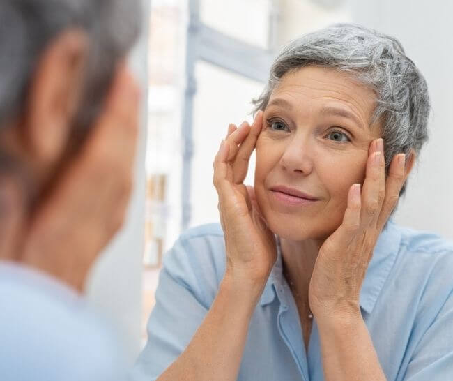 Aging woman smiling at herself in the bathroom mirror