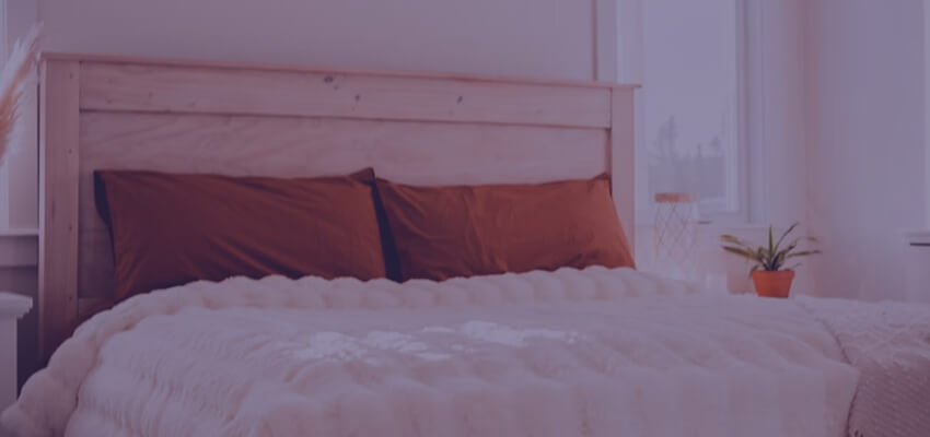 Comfortable bed with plush white comforter and orange pillows