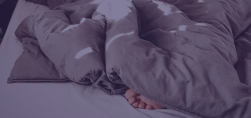 Person sleeping under a blanket with foot exposed