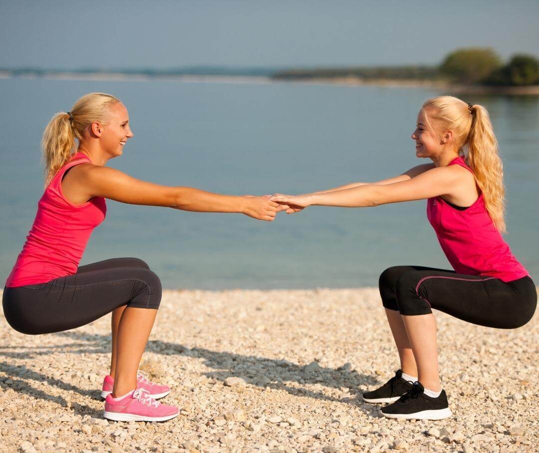 two women on beach stretching and exercising