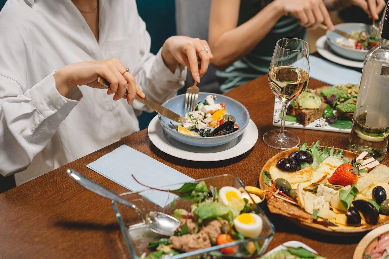 woman-at-dinner-party-eating-salad-drinking-wine