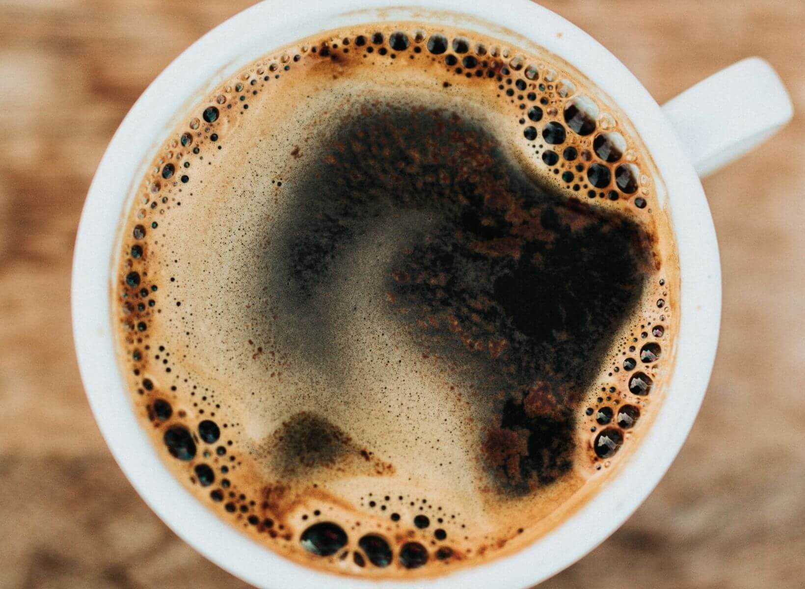 A close up overhead shot of a white mug with black coffee