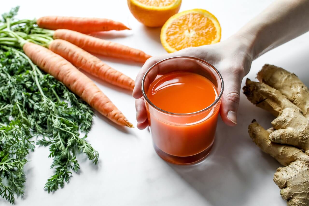 woman-holding-glass-of-carrot-orange-and-ginger-juice