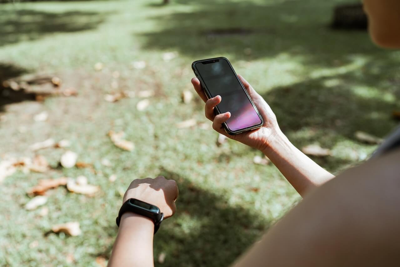 person-with-fitness-bracelet-using-smartphone