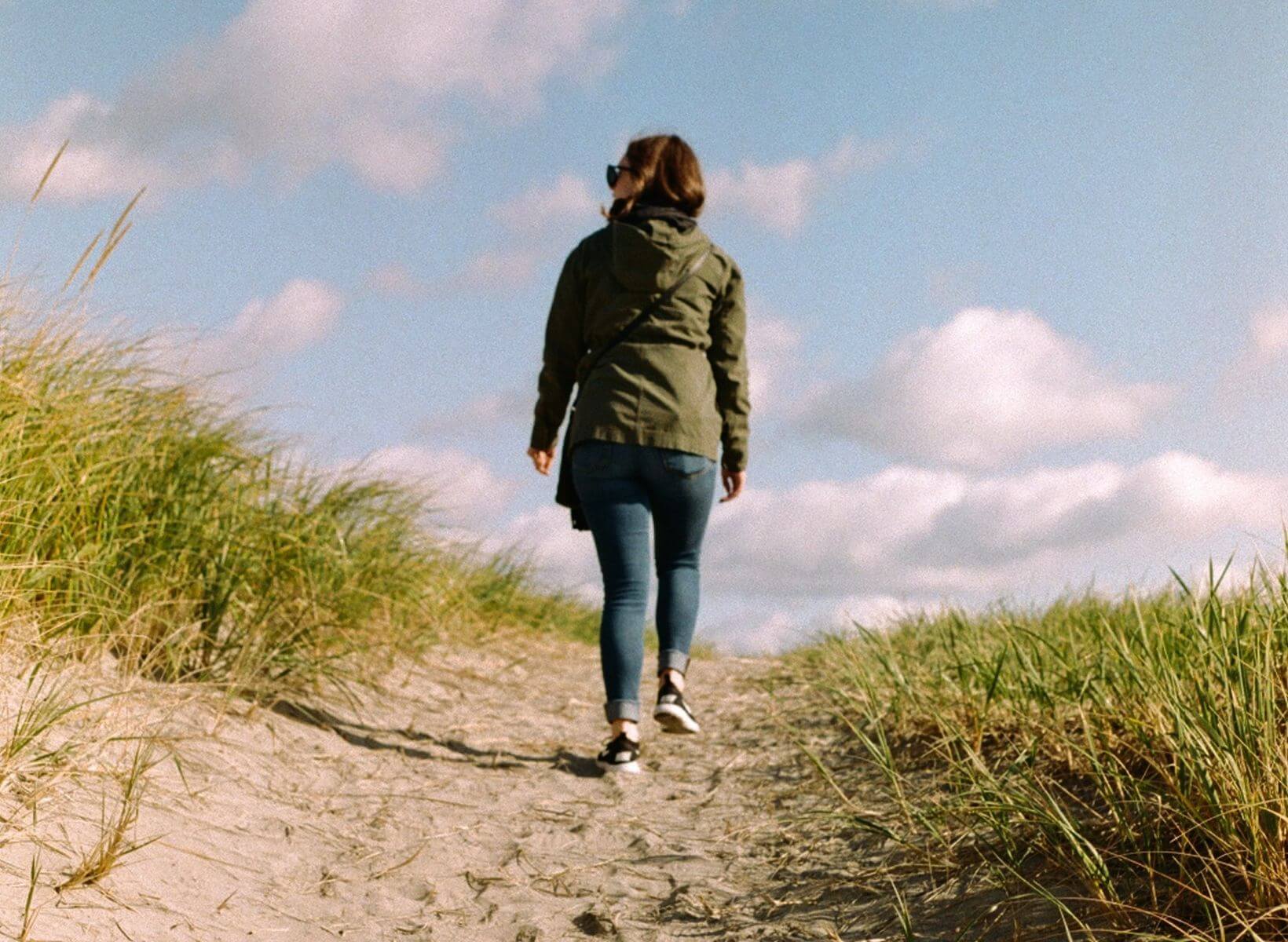 Woman walking away from the camera on a dirt path