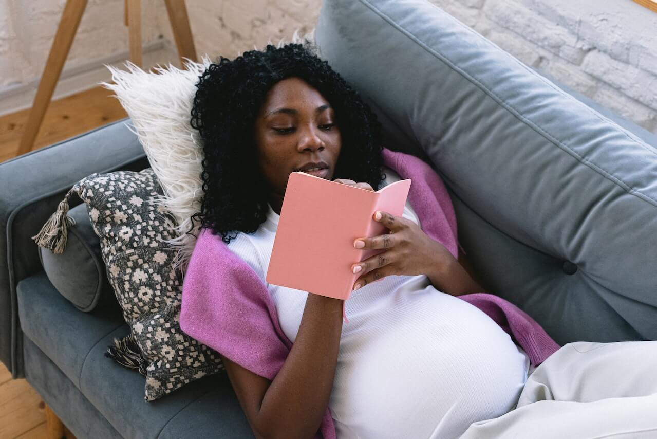 pregnant-woman-journaling-laying-in-her-couch