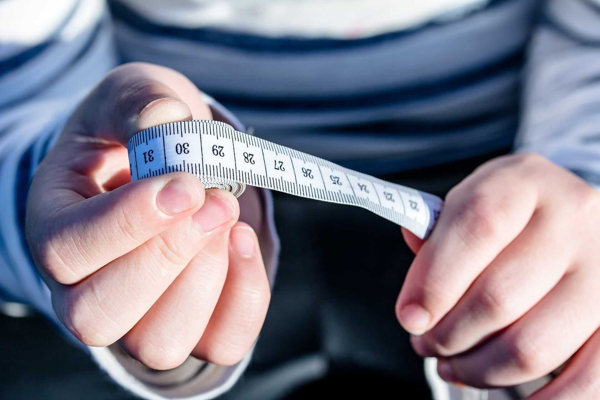 A-person-holding-a-measuring-tape-fat-loss-vs-weight-loss